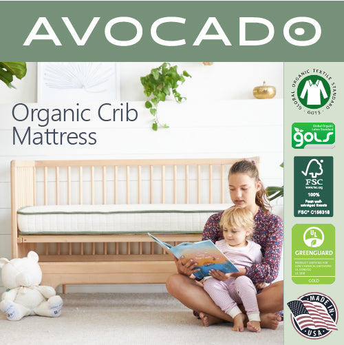 A picture of a mother and her baby reading in front of an Avocado Organic Crib Mattress.