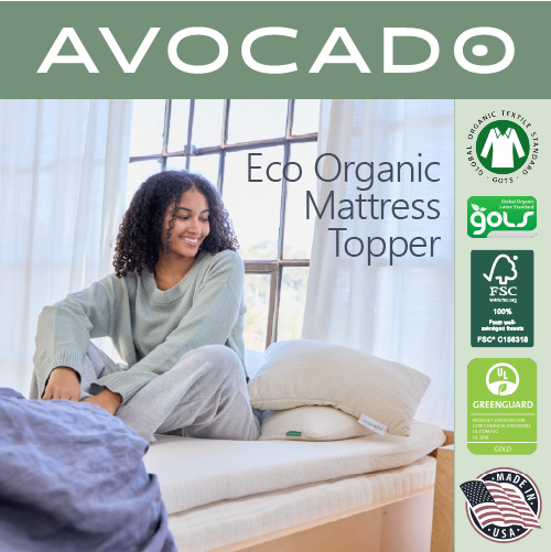A picture of a woman sitting on top of an Avocado Eco Organic Mattress Topper.